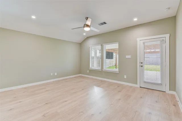 an empty room with wooden floor cabinet and windows