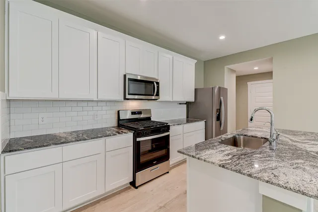 a kitchen with stainless steel appliances granite countertop a sink stove and refrigerator