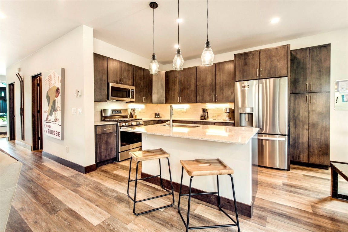 596 Fly Line Drive Silverthorne, CO 80498 - Photo 6 of 32 a kitchen with stainless steel appliances granite countertop a refrigerator a stove a sink a dining table and chairs with wooden floor