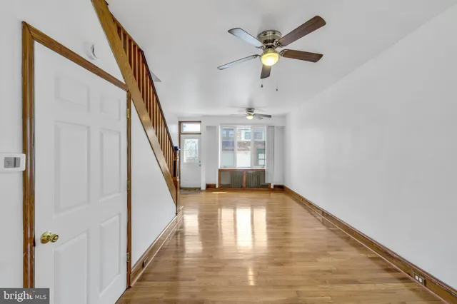 a view of empty room with wooden floor and fan