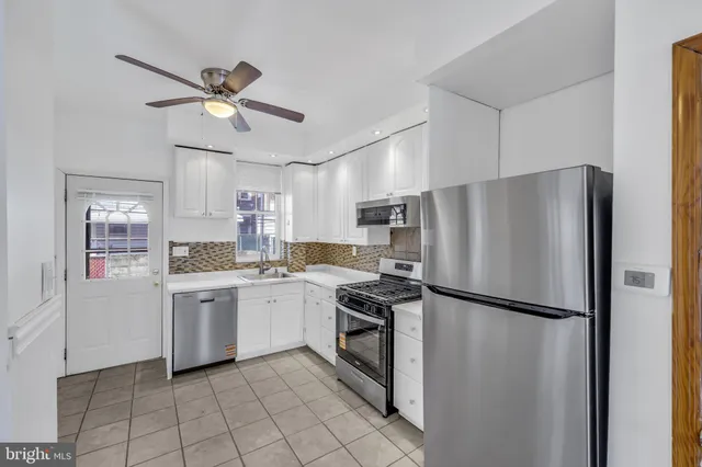 a kitchen with white cabinets and stainless steel appliances