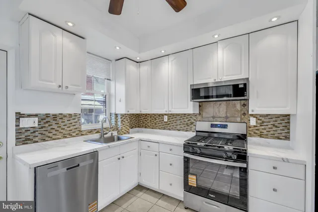 a kitchen with stainless steel appliances white cabinets and a stove a oven with white countertops