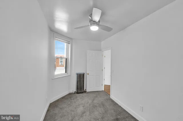 an empty room with window and ceiling fan