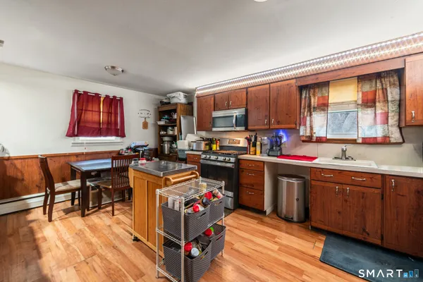 a open kitchen with stainless steel appliances granite countertop a stove top oven a sink dishwasher and cabinets with wooden floor