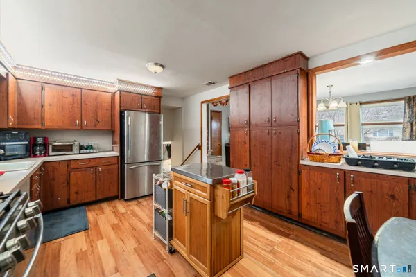 a kitchen with stainless steel appliances granite countertop a refrigerator a stove top oven a sink dishwasher and wooden cabinets with wooden floor