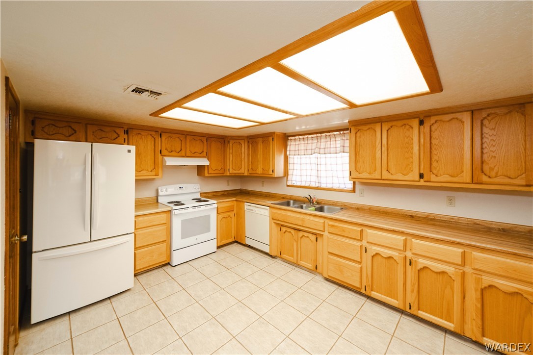 2100 East Valley View Road Kingman, AZ 86409 - Photo 12 of 53 Kitchen featuring ample wood cabinetry, a double basin stainless steel sink, and light-toned countertops