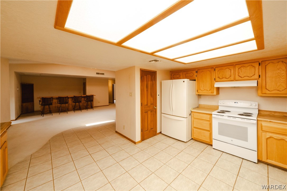 2100 East Valley View Road Kingman, AZ 86409 - Photo 13 of 53 Kitchen featuring wood cabinetry, white appliances, and tiled flooring