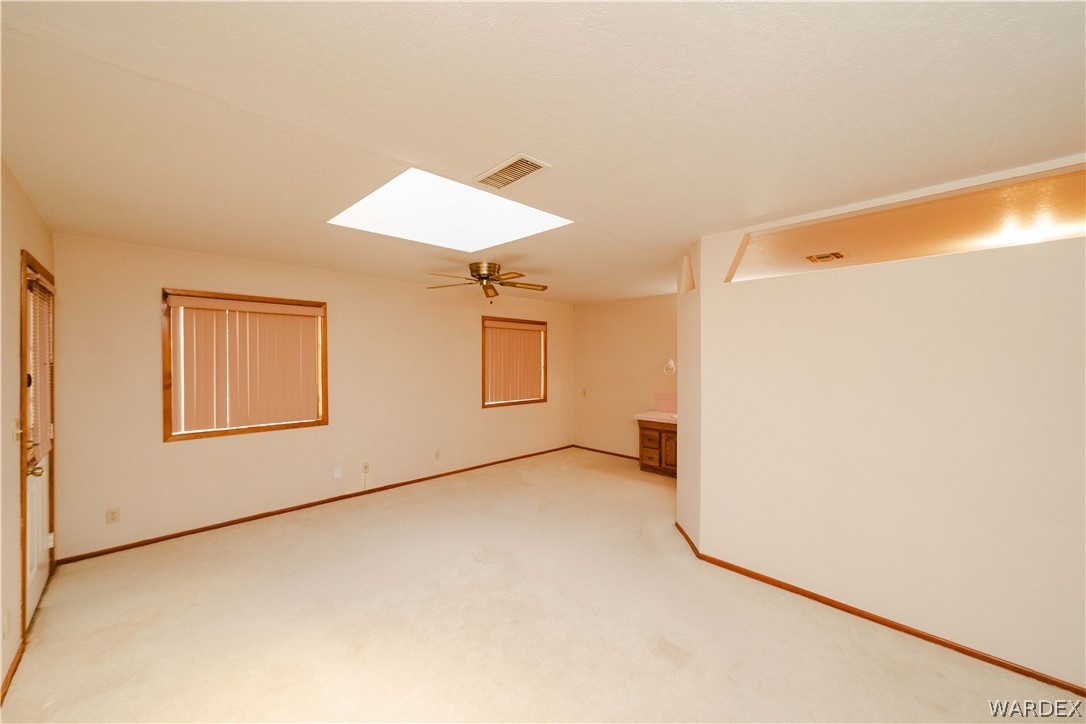 2100 East Valley View Road Kingman, AZ 86409 - Photo 19 of 53 Spacious room with a central skylight, light-colored carpeting, and wood-trim windows