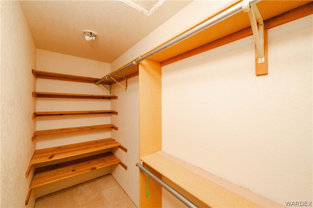 2100 East Valley View Road Kingman, AZ 86409 - Photo 23 of 53 Walk-in closet featuring extensive built-in shelving, two clothing rods, and textured wall finishes