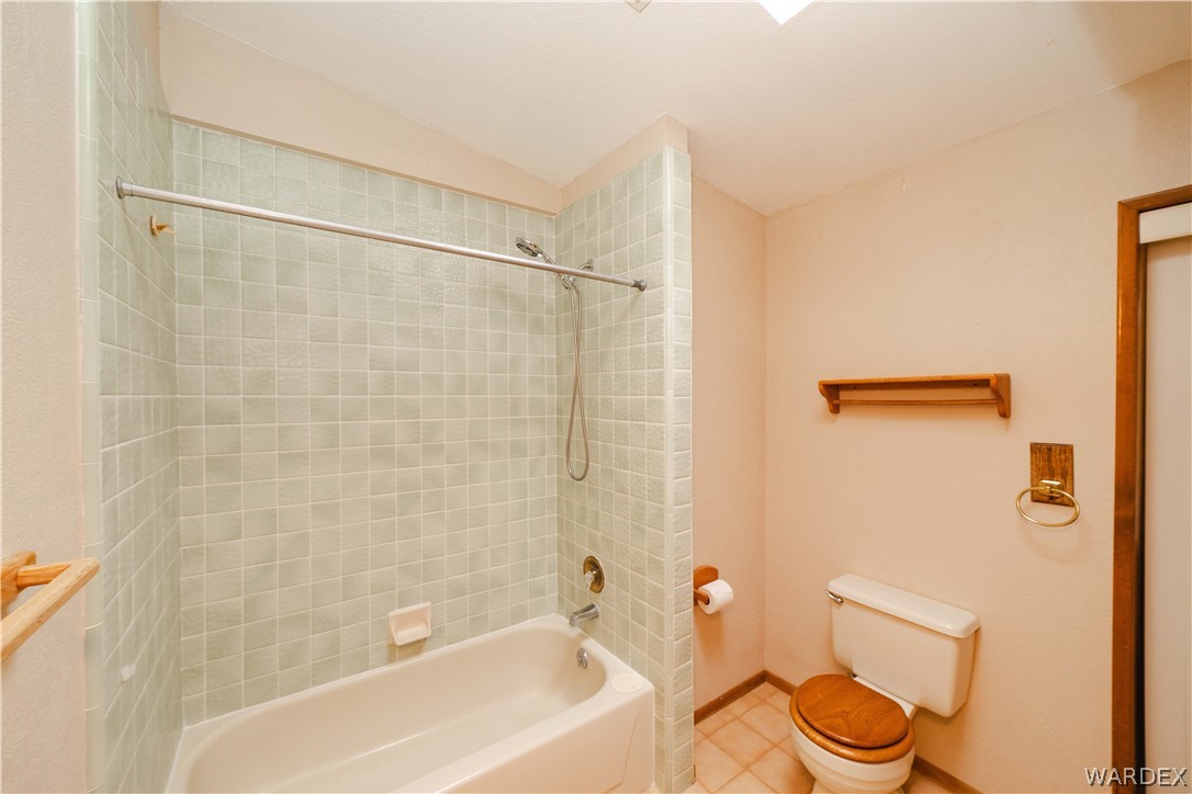 2100 East Valley View Road Kingman, AZ 86409 - Photo 24 of 53 Bathroom featuring a tiled shower surround, a white bathtub, and a toilet with a wood-finish seat