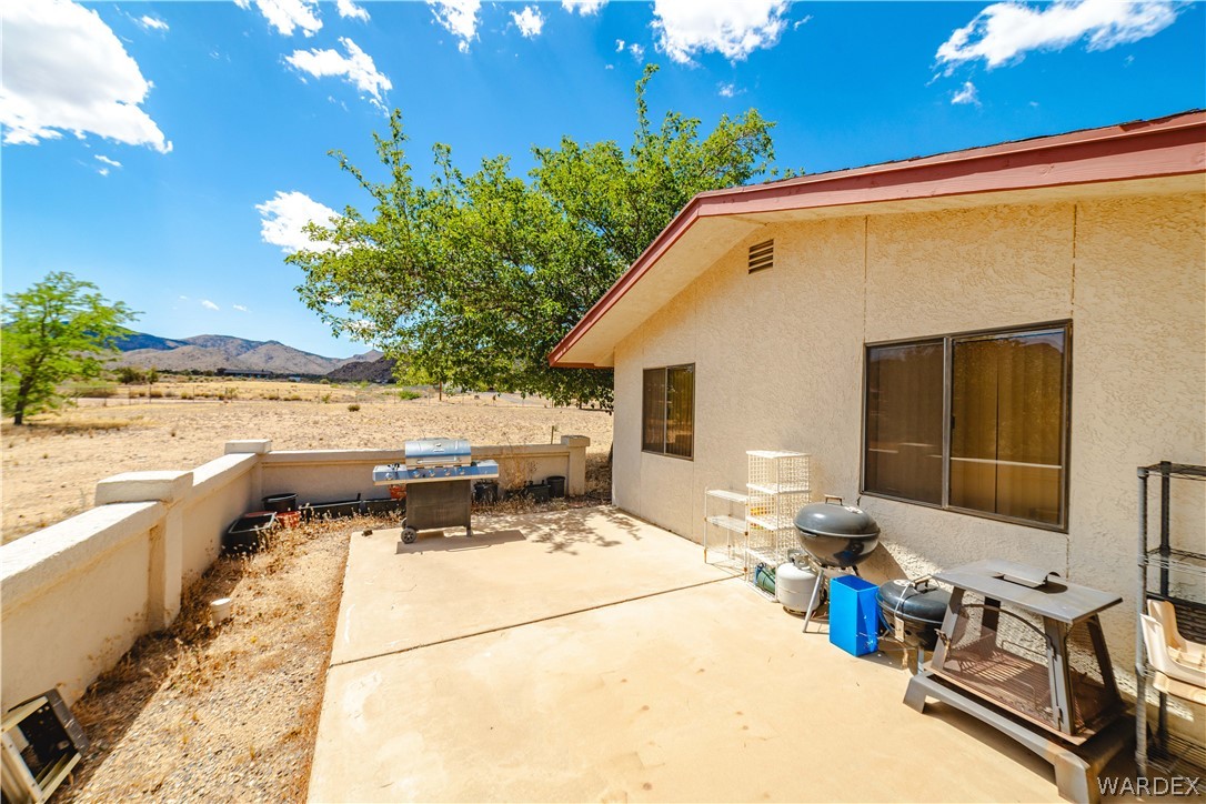 2100 East Valley View Road Kingman, AZ 86409 - Photo 38 of 53 Concrete patio area with a stucco exterior, a gently sloped roofline, and multiple windows