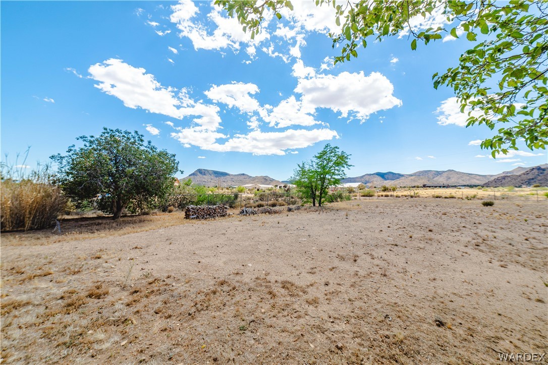 2100 East Valley View Road Kingman, AZ 86409 - Photo 41 of 53 Expansive outdoor space featuring a desert landscape with scattered trees, a distant mountainous backdrop, and a clear sky with clouds