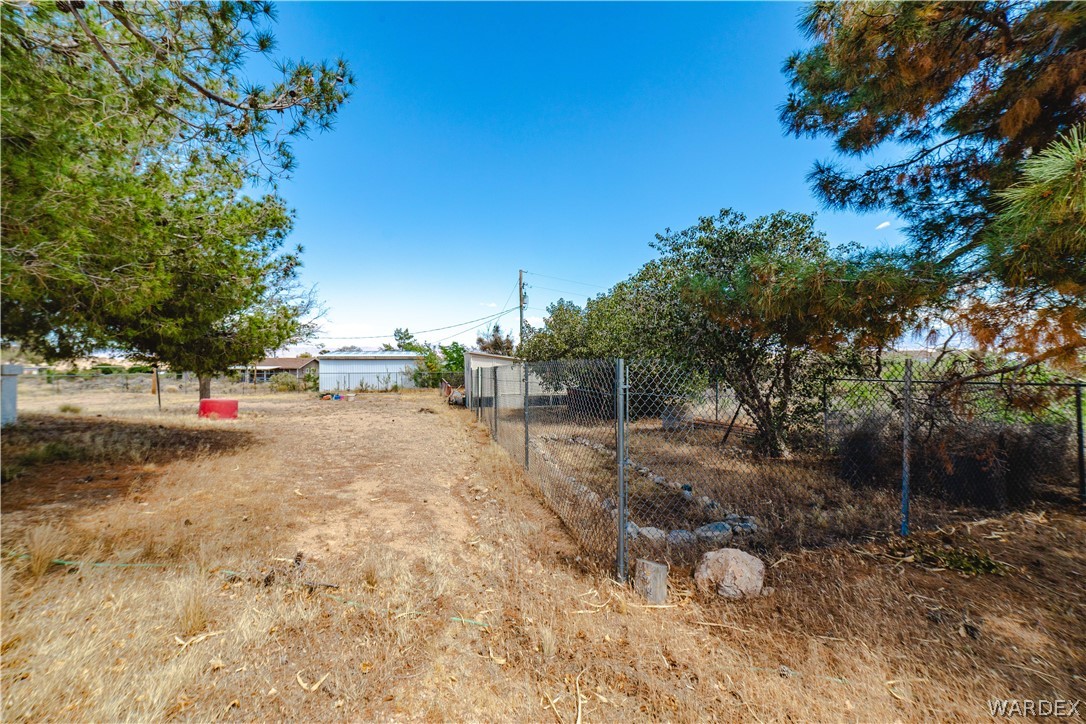 2100 East Valley View Road Kingman, AZ 86409 - Photo 45 of 53 Expansive parcel featuring mature trees, chain-link fencing, and a clear blue sky overhead