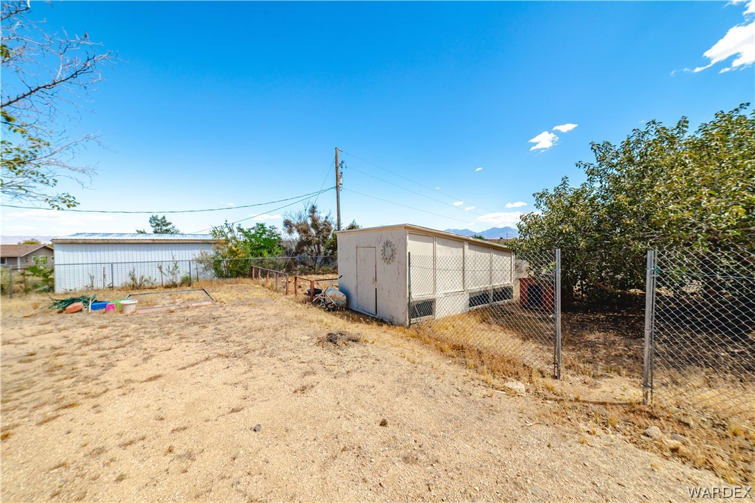 2100 East Valley View Road Kingman, AZ 86409 - Photo 46 of 53 Expansive fenced outdoor area featuring a detached white storage structure with mesh coverings