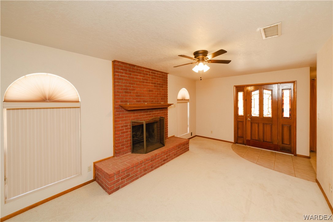 2100 East Valley View Road Kingman, AZ 86409 - Photo 5 of 53 Living area featuring a brick fireplace with a wood mantel, a ceiling fan, and light-toned carpeting