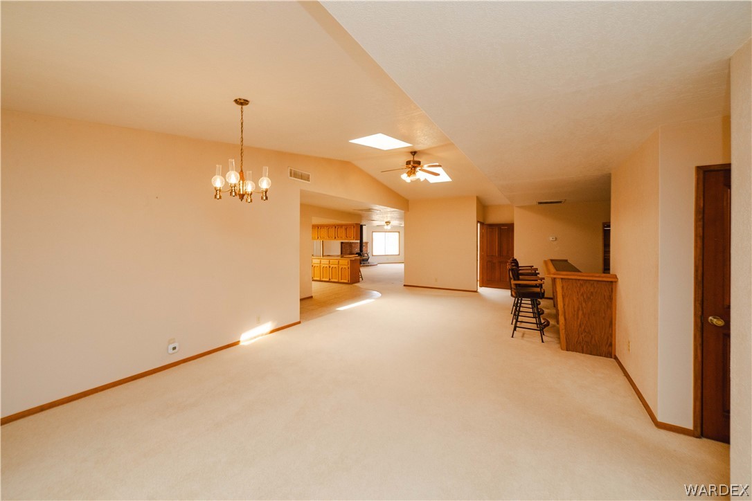 2100 East Valley View Road Kingman, AZ 86409 - Photo 7 of 53 Spacious living area featuring neutral carpeting, a brass chandelier, and an integrated wet bar with wood-finish cabinetry