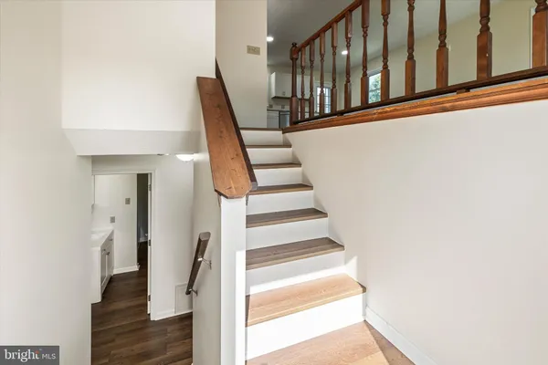 a view of staircase with lots of frames on wall and wooden floor