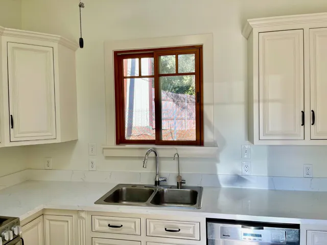 a kitchen with stainless steel appliances granite countertop white cabinets and a window