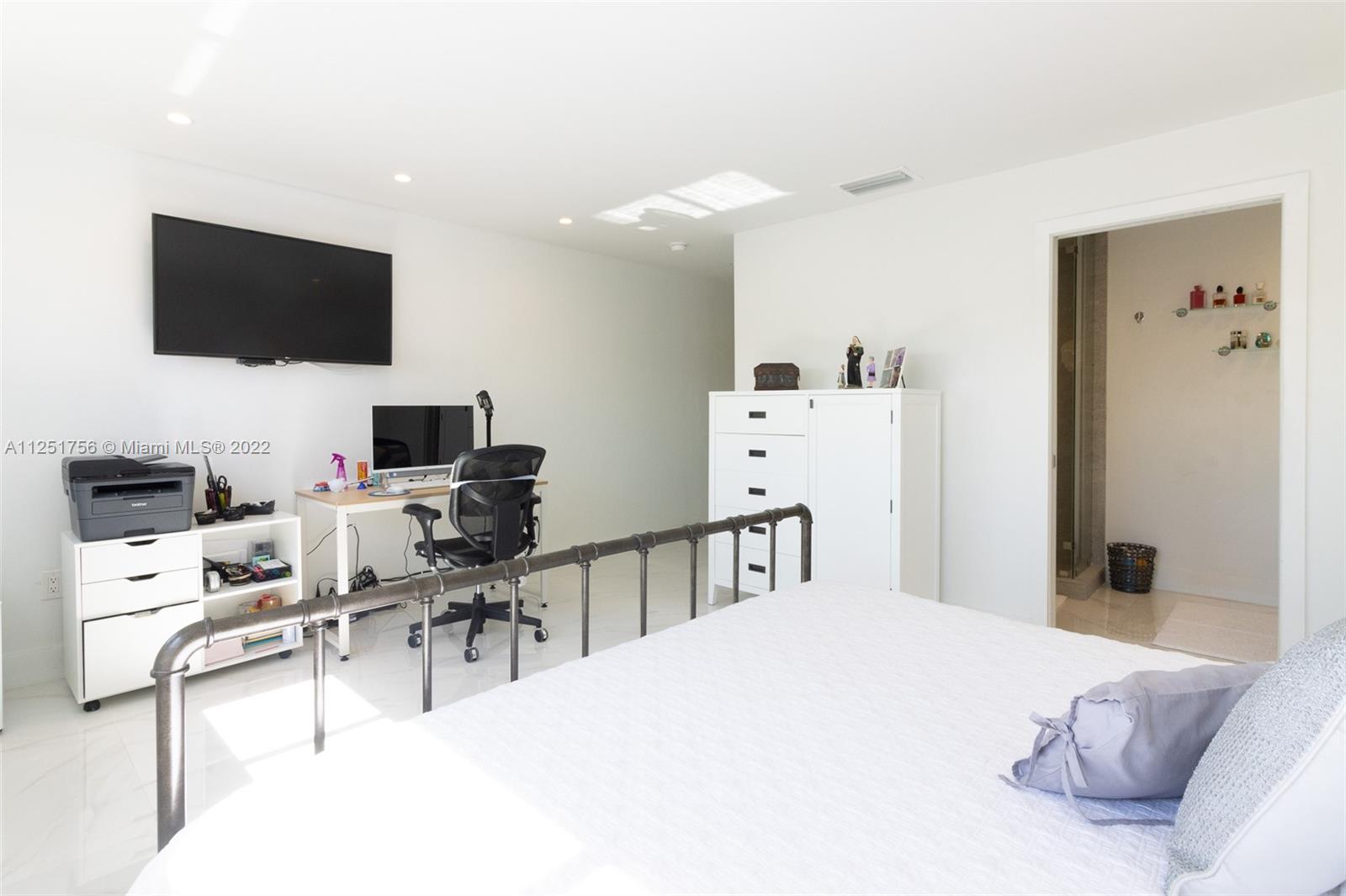 9076 Harding Avenue Surfside, FL 33154 - Photo 23 of 37 a bedroom with a bed a flat screen tv and chairs