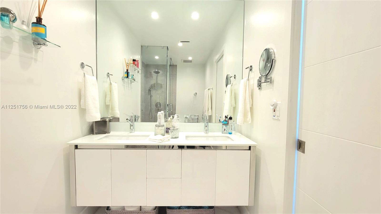 9076 Harding Avenue Surfside, FL 33154 - Photo 6 of 37 a bathroom with a sink mirror and a shower