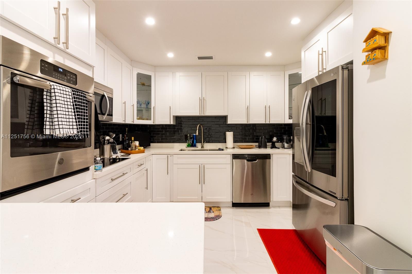 9076 Harding Avenue Surfside, FL 33154 - Photo 10 of 37 a kitchen with white cabinets and refrigerator