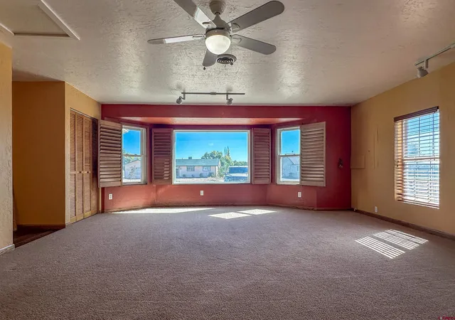 a view of empty room with windows and ceiling fan