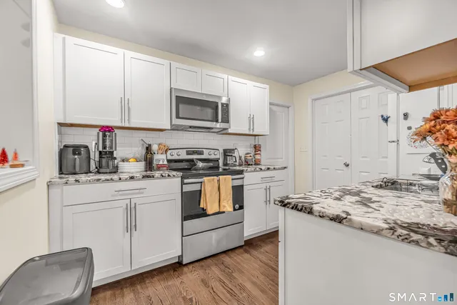 a kitchen with granite countertop white cabinets and white appliances