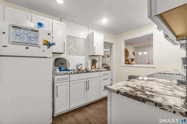 a kitchen with granite countertop white cabinets and white appliances