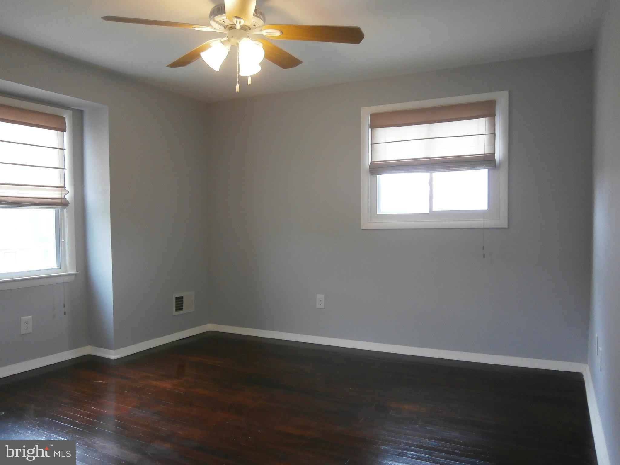5636 Whitby Road Baltimore, MD 21206 - Photo 8 of 17 an empty room with wooden floor windows and fan