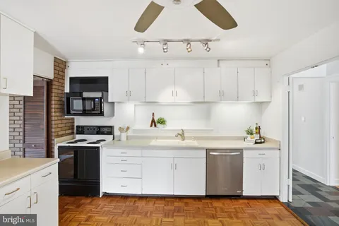a large kitchen with a stove a refrigerator a sink a stove and white cabinets