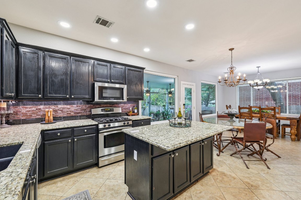 1108 Dalea Bluff Round Rock, TX 78665 - Photo 10 of 40 a kitchen with a stove a sink a microwave a dining table and chairs