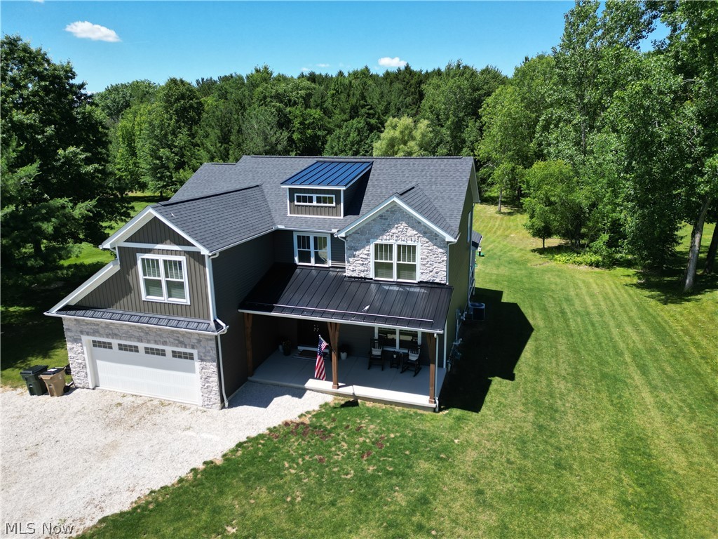 4553 Sharon Copley Road Medina, OH 44256 - Photo 24 of 32 Contemporary two-story residence featuring a gray shingle roof, stone and vertical siding exterior, a front porch with a metal roof, and an attached two-car garage
