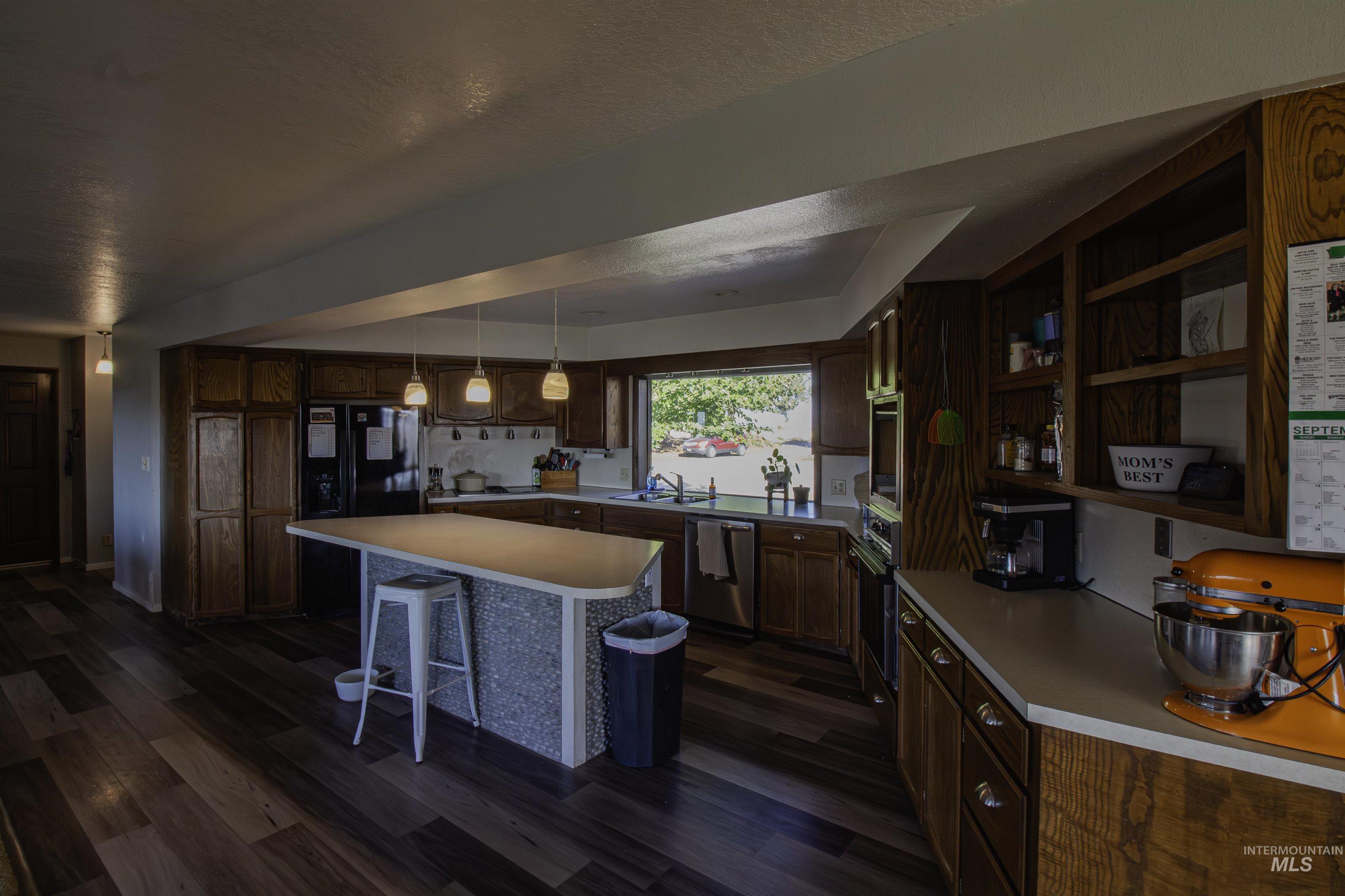 887 Overstreet Road Nyssa, OR 97913 - Photo 13 of 50 Kitchen with a breakfast bar, dark wood-type flooring, open shelves, a center island, and light countertops