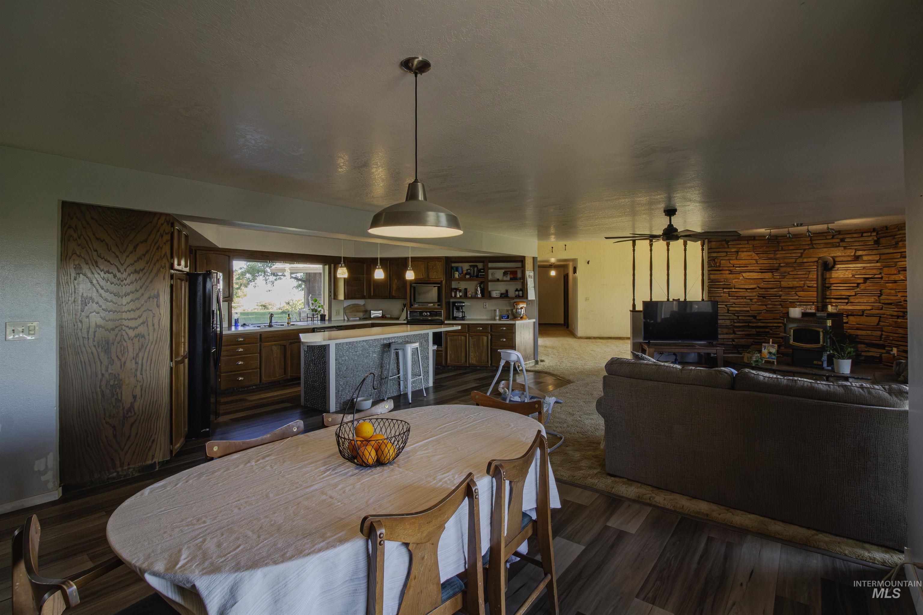 887 Overstreet Road Nyssa, OR 97913 - Photo 15 of 50 Dining room featuring a wood stove, ceiling fan, and dark wood-type flooring