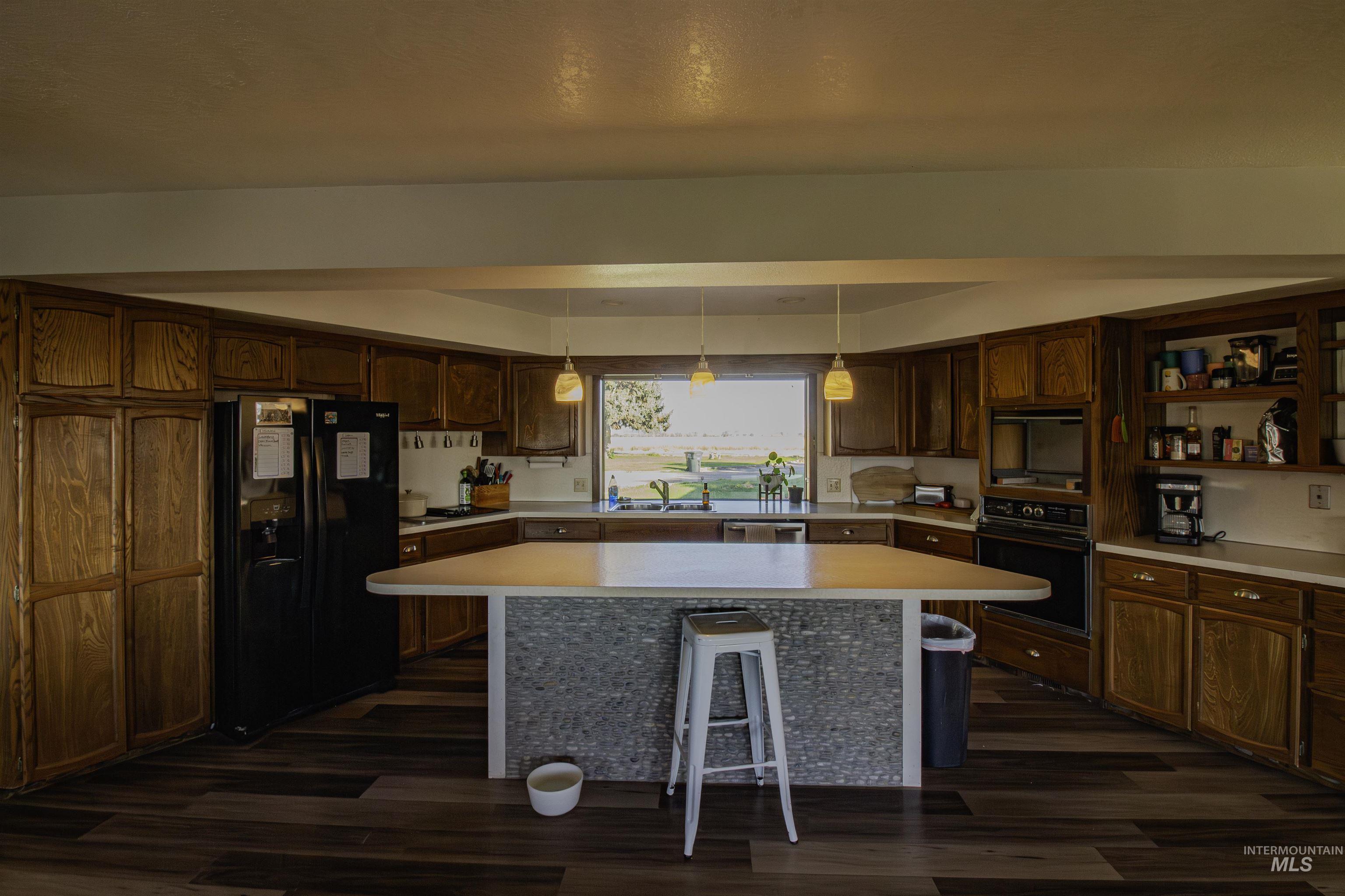 887 Overstreet Road Nyssa, OR 97913 - Photo 16 of 50 Kitchen with black appliances, a breakfast bar, light countertops, and a kitchen island