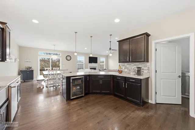 a large kitchen with stainless steel appliances granite countertop a stove top oven a sink dishwasher a dining table and chairs with wooden floor