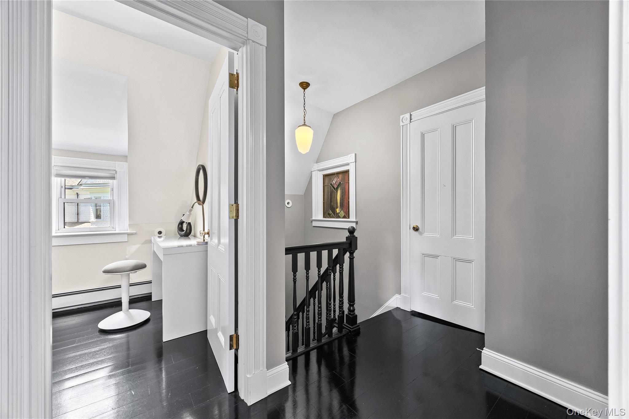 19 Howe Place Bronxville, NY 10708 - Photo 22 of 37 Third-level hallway featuring dark wood-finish flooring, a white paneled door, and a traditional spindle railing