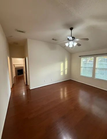 an empty room with wooden floor and windows