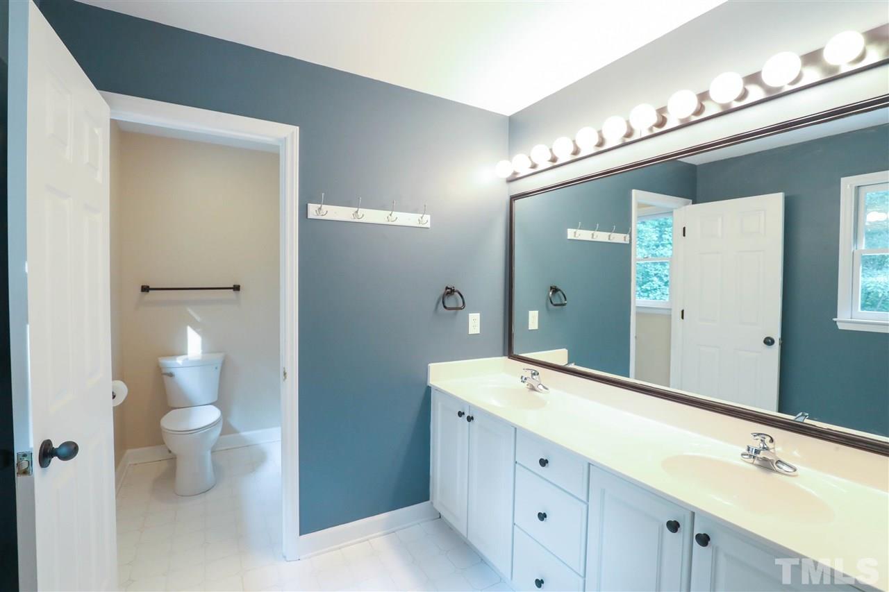8925 Ball Road Bahama, NC 27503 - Photo 19 of 28 a spacious bathroom with a double vanity sink a toilet and a mirror