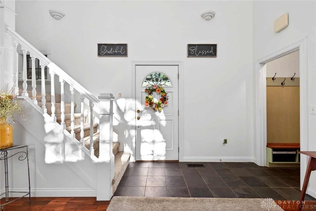 330 South Alpha Bellbrook Road Bellbrook, OH 45305 - Photo 8 of 87 This inviting entryway features a grand staircase and durable tile flooring, creating a warm welcome.