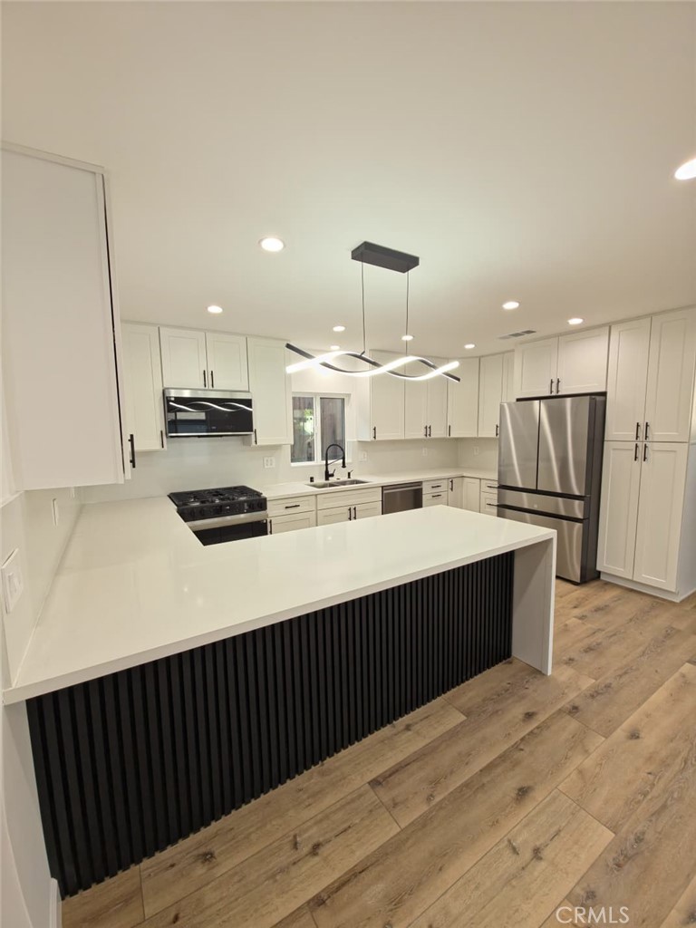 7045 Nestle Avenue Reseda, CA 91335 - Photo 3 of 15 a kitchen with stainless steel appliances a sink a stove a refrigerator and cabinets