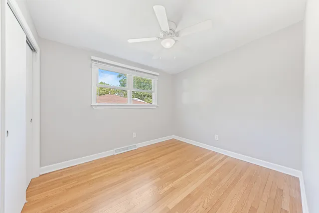 an empty room with a window and a ceiling fan