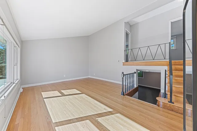 a view of an empty room with wooden floor and a fireplace