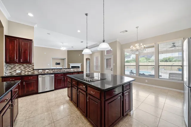 a kitchen with stainless steel appliances granite countertop a stove a sink dishwasher a refrigerator and a wooden cabinets