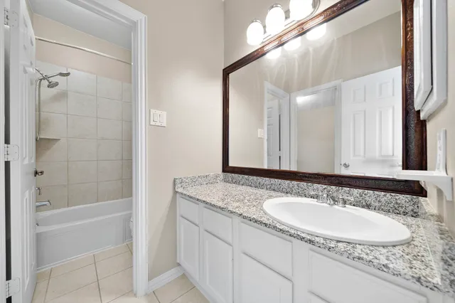 a bathroom with a granite countertop sink a mirror and a bathtub