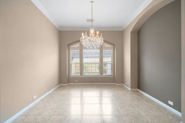 a view of an empty room with windows and chandelier