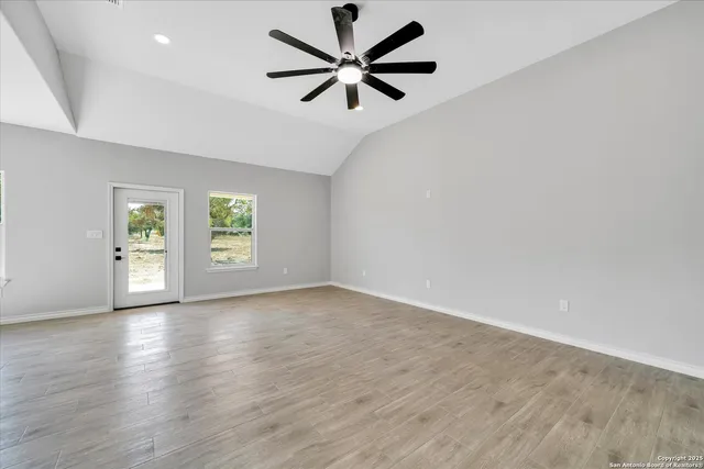 an empty room with windows and ceiling fan