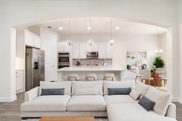 a living room with furniture white cabinets and a chandelier