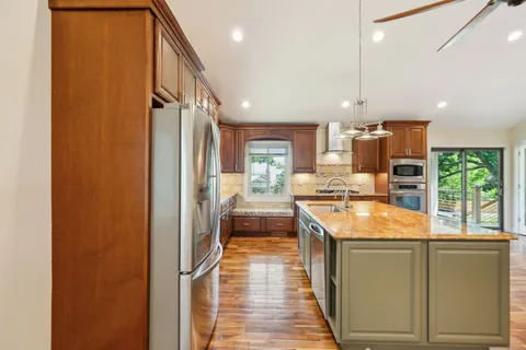 a kitchen with stainless steel appliances granite countertop a sink a stove and a wooden floors