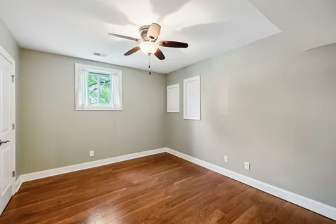 an empty room with wooden floor and ceiling fan